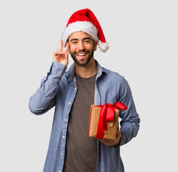 Giovane che indossa santa cappello divertente e felice facendo un gesto di vittoria