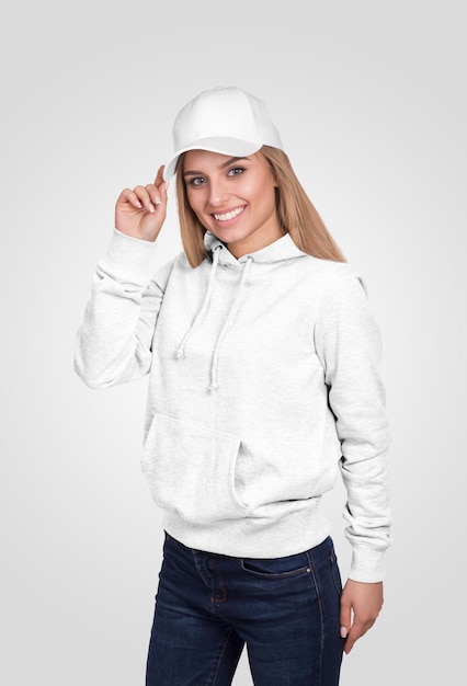 Giovane donna con cappuccio bianco e cappello sorride alla telecamera