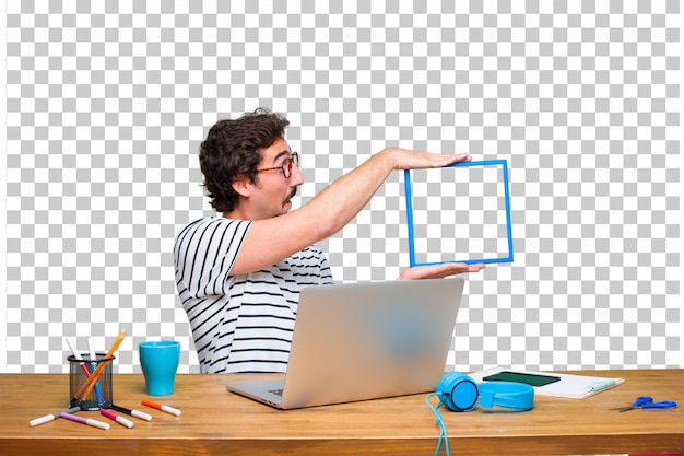 Giovane grafico pazzo su una scrivania con un computer portatile e con una cornice
