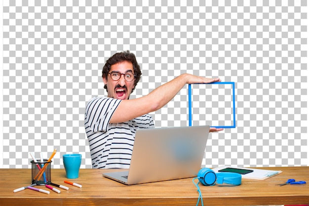 Giovane grafico pazzo su una scrivania con un computer portatile e con una cornice