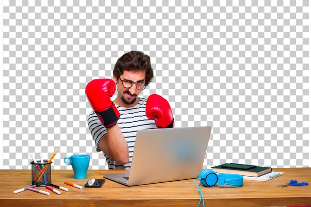 Giovane grafico pazzo su una scrivania con un computer portatile e indossando i guantoni da boxe