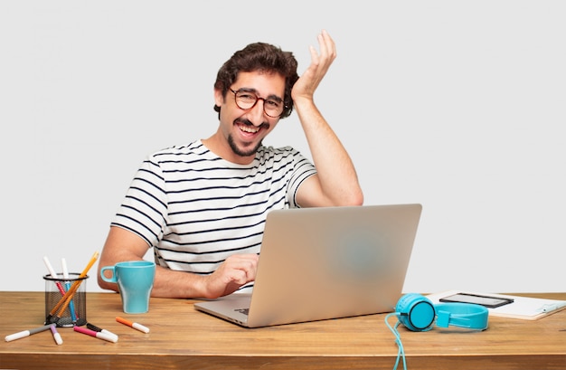 giovane graphic designer barbuto con un laptop che realizza felicemente alcune buone e sorprendenti novità