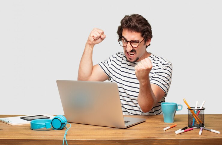 PSD giovane graphic designer barbuto con un laptop con una posa arrabbiata, aggressiva e minacciosa