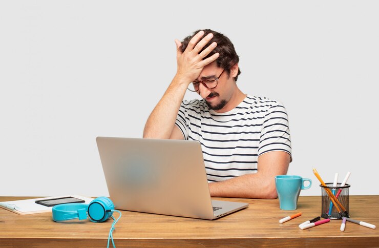 PSD giovane graphic designer con la barba con un laptop con uno sguardo triste di delusione e sconfitta