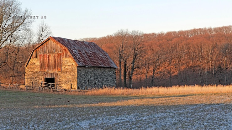 PSD une grange de pierre rustique au coucher du soleil dans un champ enneigé avec des arbres d'automne