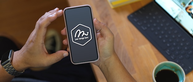 Gros plan sur les mains tenant la maquette de l'écran du smartphone