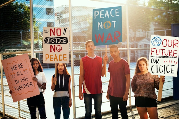Gruppo di adolescenti che protestano concetto pacifista di pace della giustizia dei manifesti della tenuta di dimostrazione