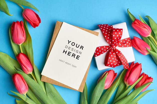 Grußkartenmodell mit geschenkbox und roten tulpenblumen