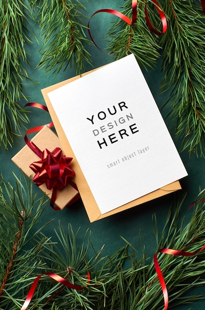 Grußkartenmodell mit Weihnachtsgeschenkbox und Kiefernzweigen auf Grün