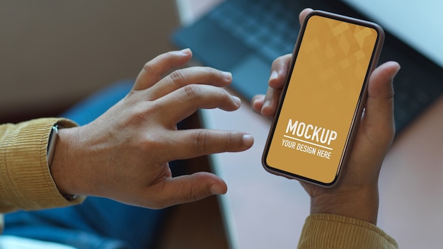 Hände mit Smartphone-Modell auf Arbeitstisch