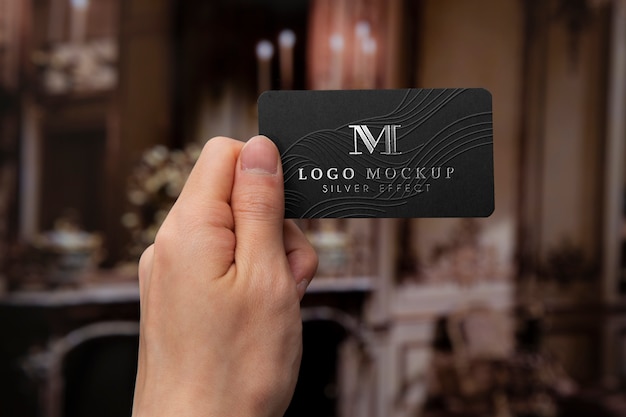 Handgehaltene Visitenkarte mit silbernem Logo