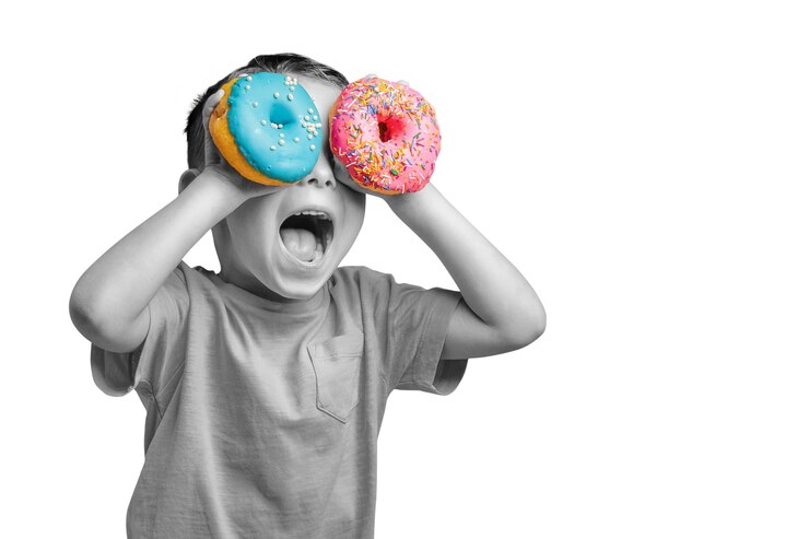 PSD happy cute boy is having fun played with donuts on png background bright photo of a child