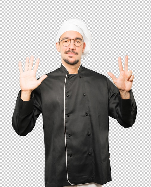 Happy young chef doing a number eight gesture with his hands