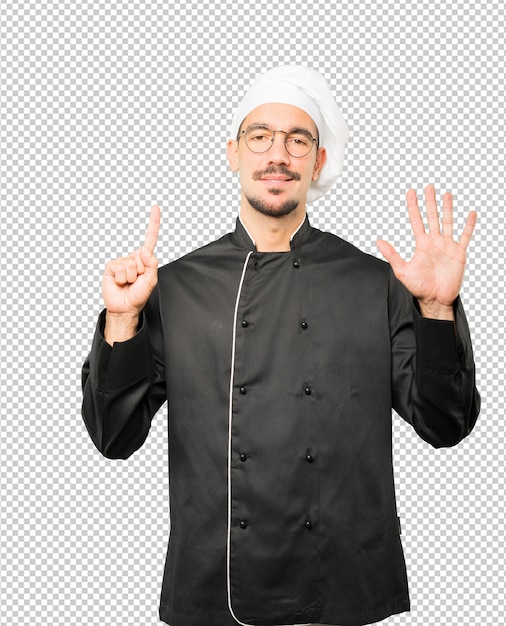 Happy young chef doing a number six gesture with his hands