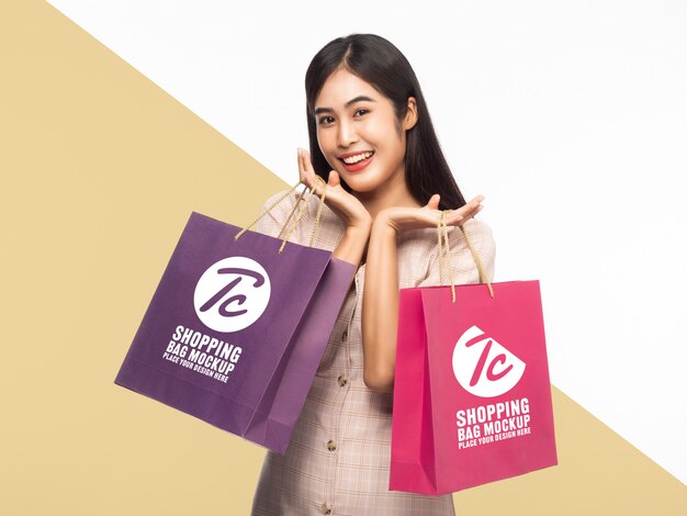 Hermosa mujer asiática sonriente con plantilla de maqueta de bolsas de compras para su diseño