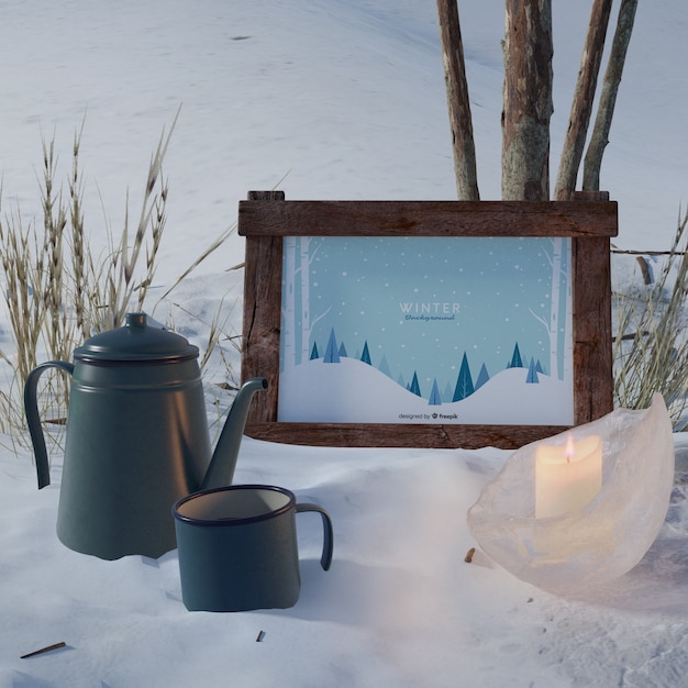 Hervidor de agua y taza junto al marco con tema de invierno