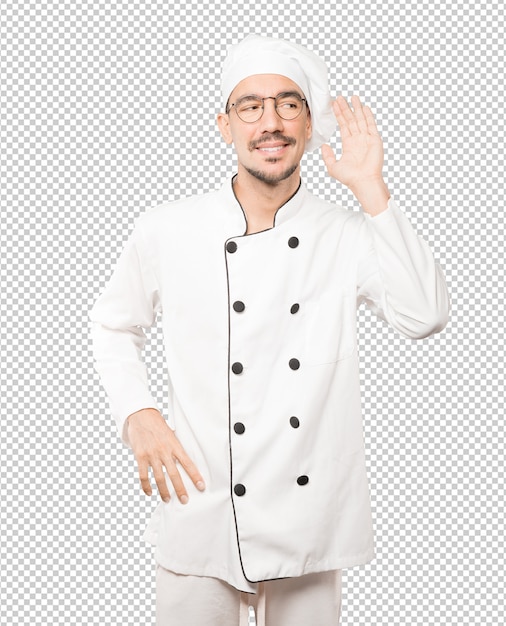Heureux jeune chef souriant et faisant un geste d'essayer d'entendre quelque chose