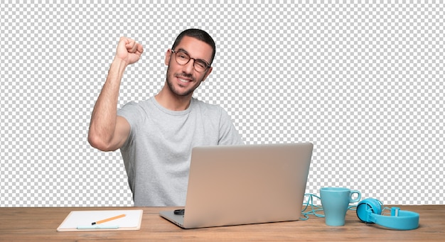 Heureux jeune homme assis à son bureau avec un geste de fête