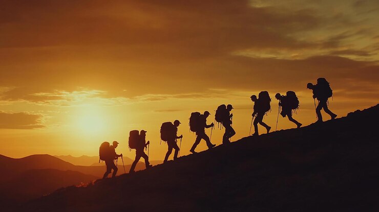 PSD hikers silhouettes ascending mountain at sunset