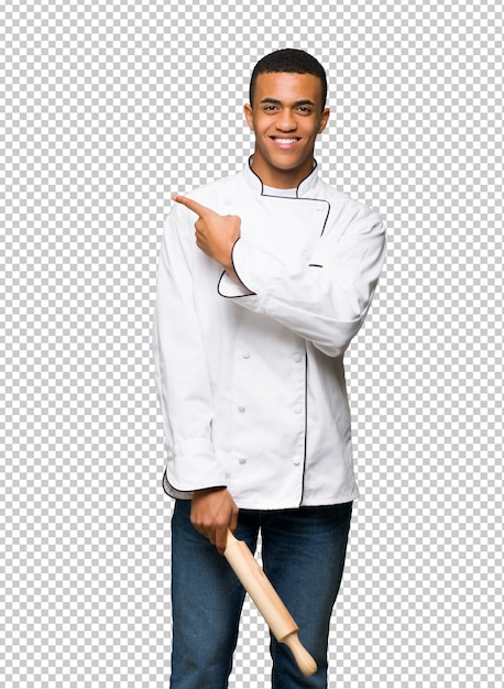 Hombre afroamericano joven del cocinero que señala al lado para presentar un producto