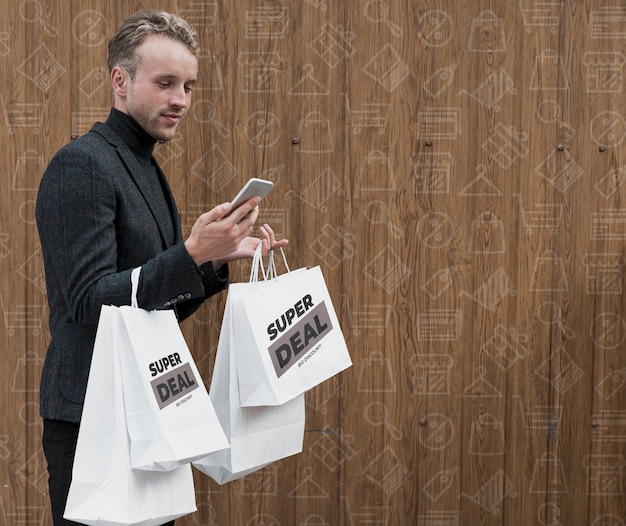 Hombre con bolsas de compras revisando teléfono