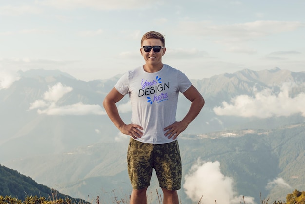 Hombre en camiseta blanca posando frente a una vista de la montaña