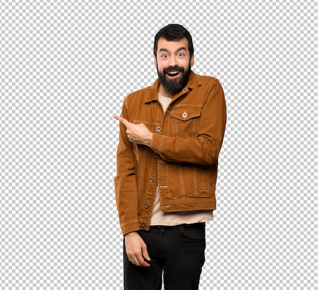 Hombre guapo con barba sorprendido y apuntando a un lado.
