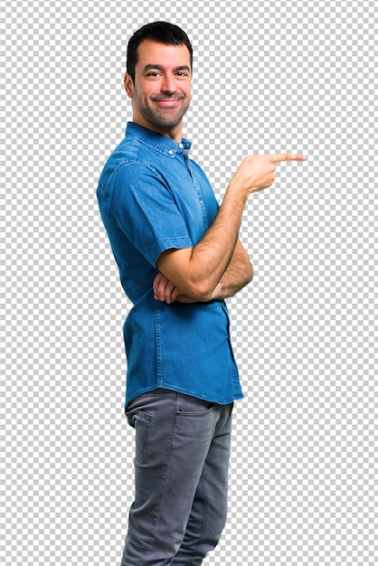 Hombre guapo con camisa azul apuntando con el dedo hacia un lado y presentando un producto