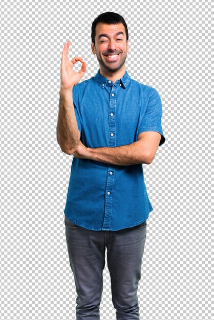 Hombre guapo con camisa azul que muestra un signo aceptable con los dedos