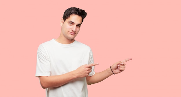 hombre guapo joven sonriendo y apuntando hacia el lado con ambas manos