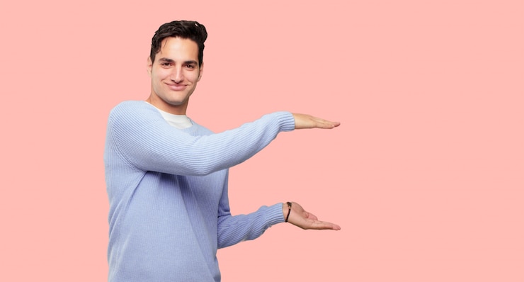 PSD hombre guapo joven sonriendo con una expresión satisfecha que muestra un objeto o concepto