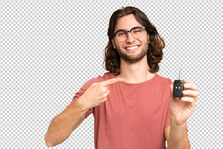 PSD hombre guapo joven sosteniendo las llaves del auto sobre un fondo aislado y apuntándolo