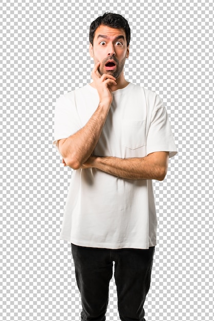 Hombre joven con camisa blanca sorprendido y sorprendido mientras se mira a la derecha. Emoción facial expresiva