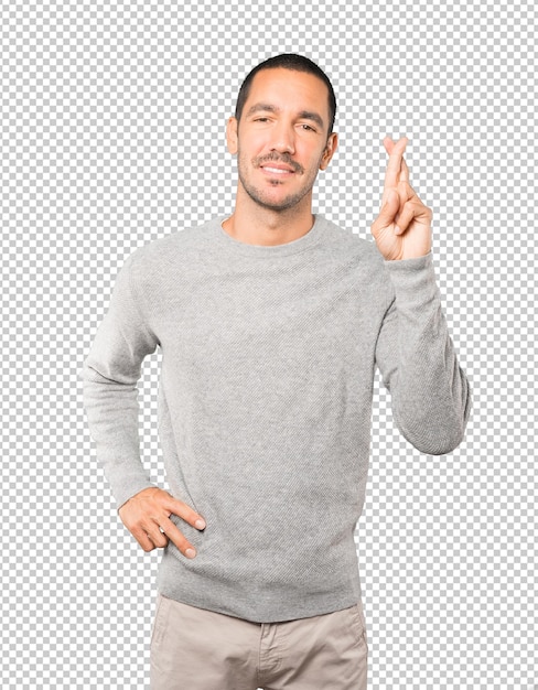 Hombre joven feliz haciendo un gesto de dedos cruzados