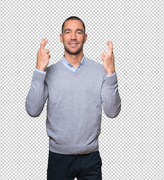 Hombre joven feliz haciendo un gesto de dedos cruzados
