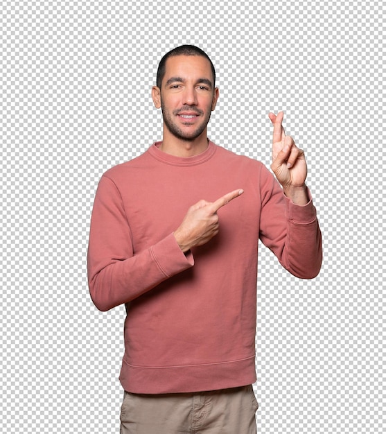 Hombre joven feliz haciendo un gesto de dedos cruzados