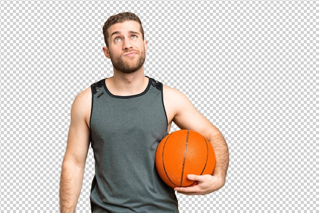 Hombre joven guapo jugando al baloncesto sobre el fondo de la clave de croma aislado y mirando hacia arriba