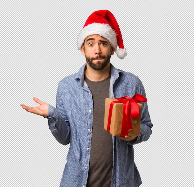 Hombre joven con sombrero de santa confundido y dudoso