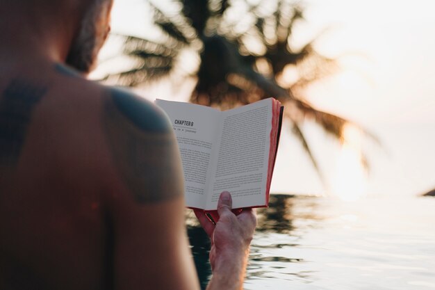 Hombre leyendo un libro en la piscina