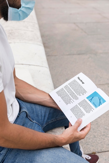 Hombre con máscara en el libro de lectura de la calle