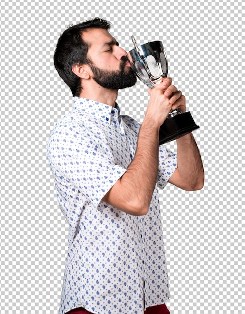 Hombre moreno hermoso con la barba que sostiene un trofeo