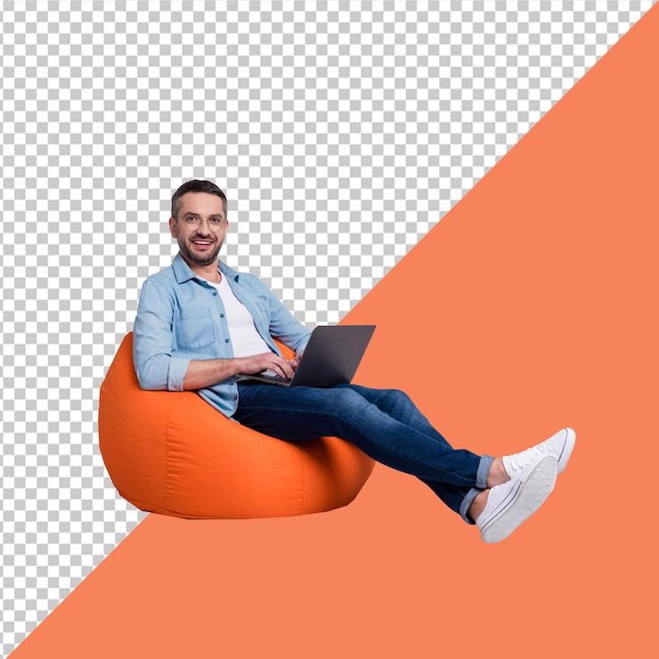 El hombre de PSD se sienta en una silla naranja con una computadora portátil en el regazo con fondo transparente