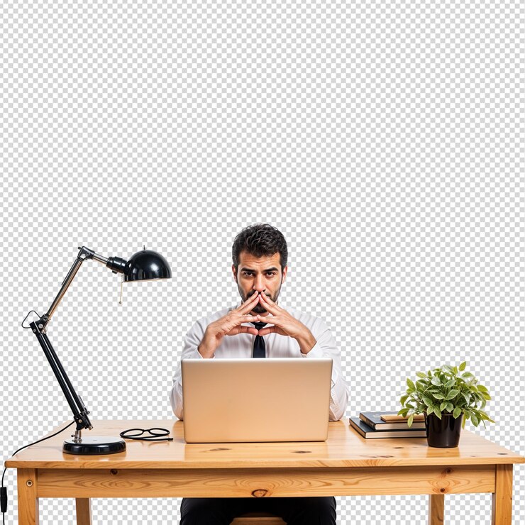 un hombre se sienta en un escritorio con una computadora portátil y una planta en ella