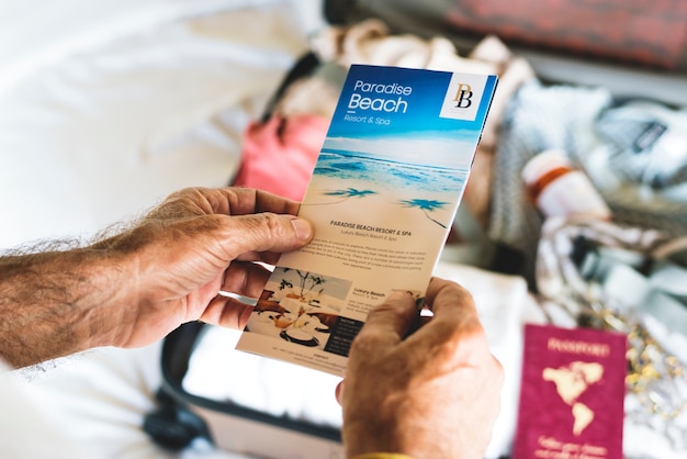 Hombre sosteniendo un folleto de viajes a la playa