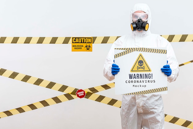 Hombre en traje de materiales peligrosos con una maqueta de coronavirus de advertencia