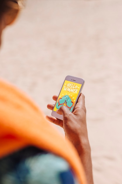 PSD hombre usando mockup de smartphone en la playa