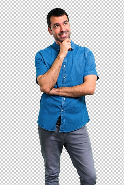 Homem bonito com camisa azul em pé e pensando uma idéia