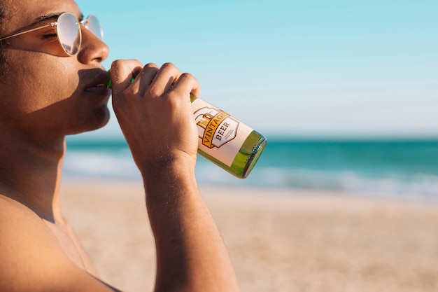 Homem com maquete de garrafa de cerveja na praia
