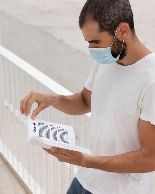 Homem com máscara na rua lendo livro