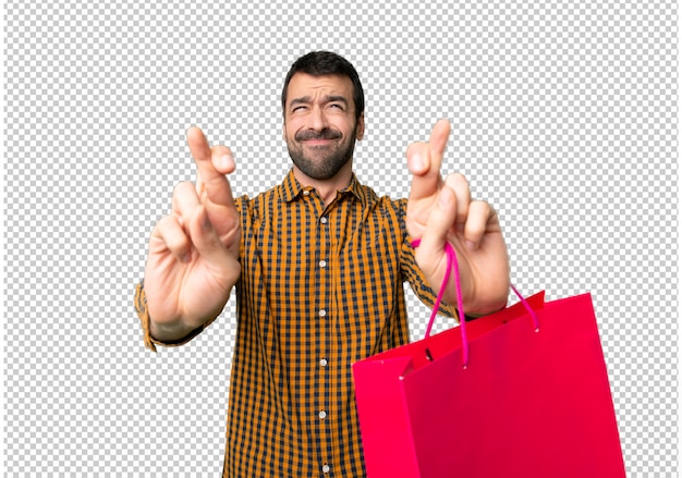 Homem com sacos de compras com os dedos cruzando e desejando o melhor